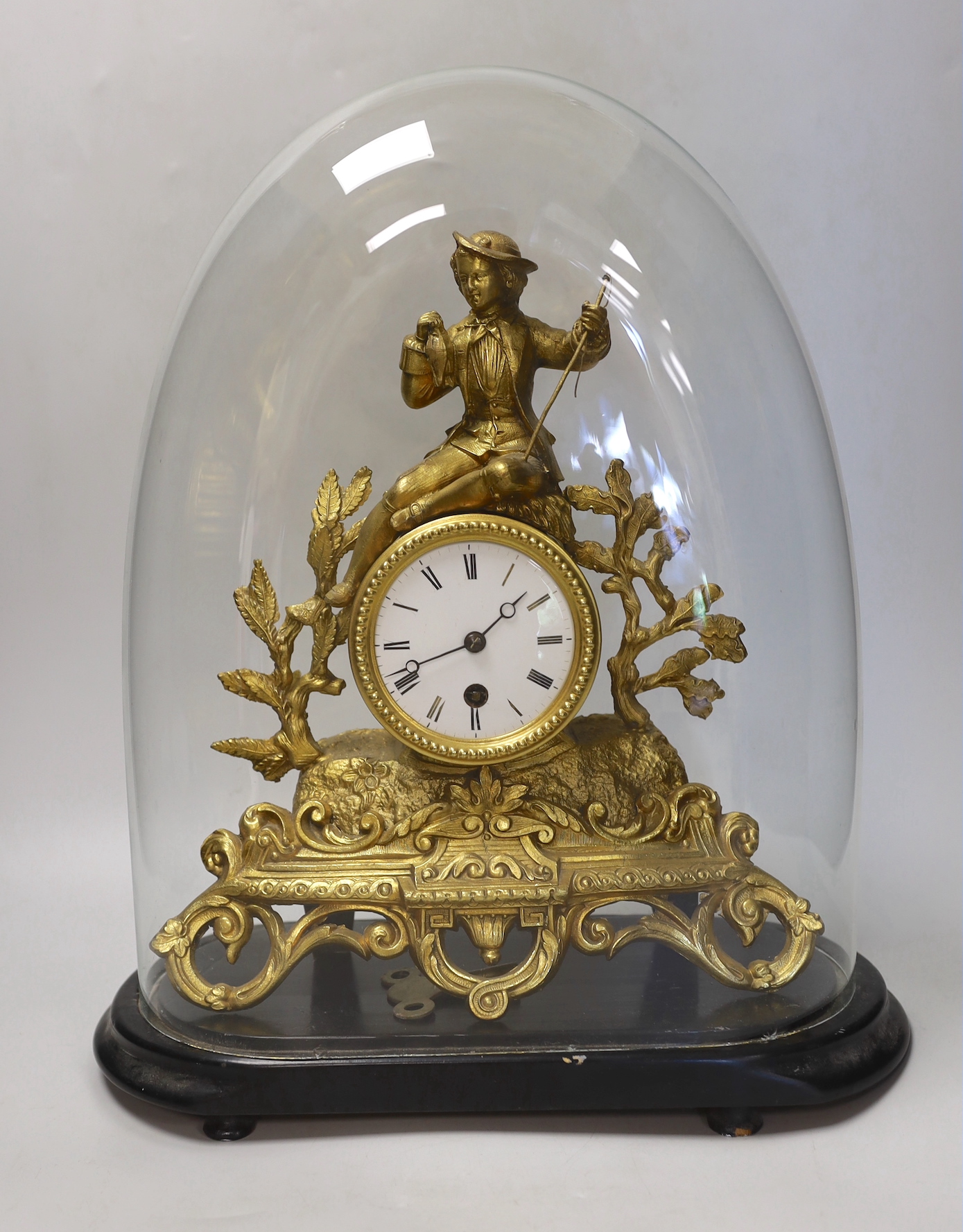 A an ornate figural gilt-spelter mantel clock, under glass dome on stand, 40cm high